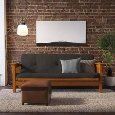 a living room with a couch, chair and ottoman in front of a brick wall