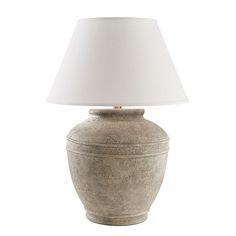 a lamp that is on top of a white table cloth next to a gray vase