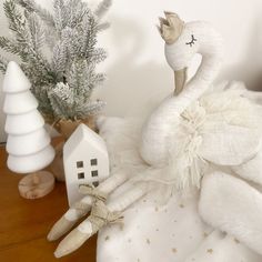 a stuffed swan sitting on top of a bed next to a white house and christmas tree