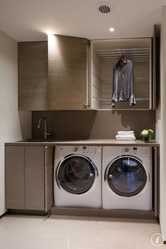 a washer and dryer in a small room with clothes hanging on the rack