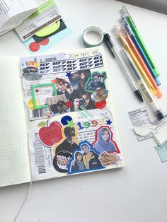 an open notebook sitting on top of a white table covered in stickers and pens