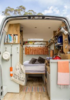 the interior of an rv with a bed and storage area in the side door open