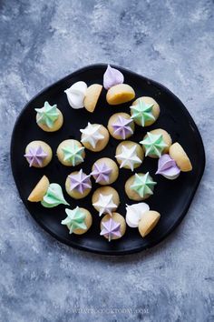 a black plate topped with star shaped cookies on top of a gray tablecloth covered in icing