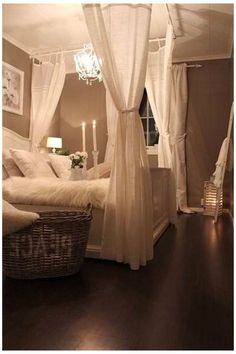 a white canopy bed sitting in a bedroom under a chandelier