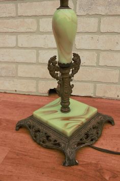 a green lamp sitting on top of a wooden table next to a brick wall and floor