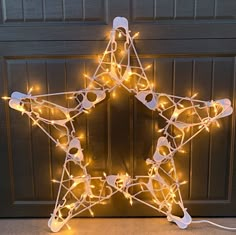 a star shaped light up decoration with string lights on the bottom and sides, sitting in front of a garage door