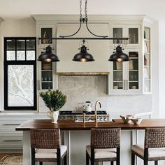 a kitchen with an island and three lights hanging from it's ceiling above the counter