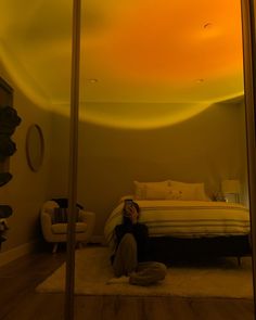 a woman sitting on the floor in front of a bed with a yellow sky overhead