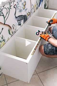 a man kneeling on the floor with some tools in his hands and an orange glove