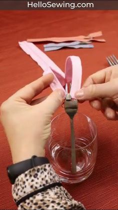 two hands holding scissors over a bowl with paper on the table next to each other