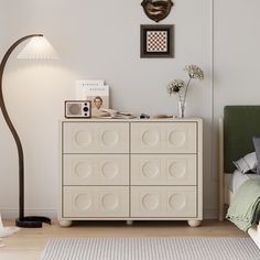 a bedroom with a bed, lamp and dresser