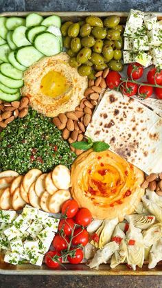 a tray filled with different types of food including crackers, cucumbers and olives