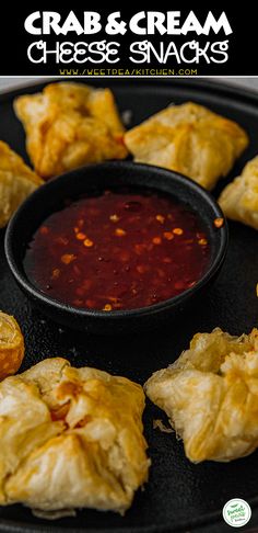 crab and cream cheese snacks on a black plate with dipping sauce in a bowl next to them