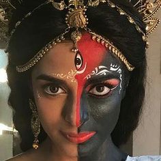 a woman with painted face and headdress posing for a photo in front of a mirror