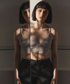 a woman standing in front of a mirror wearing black pants and a silver bra top