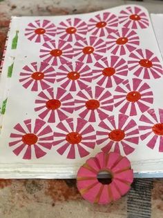 a piece of paper with red and white designs on it next to a pink pinwheel