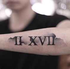 a man's arm with roman numerals tattooed on the upper half of his arm