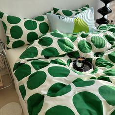 a bed with green and white polka dots on the comforter, pillows and pillow cases