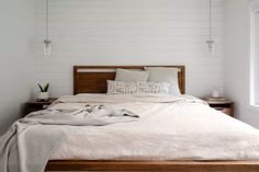 a bed with white sheets and pillows in a bedroom