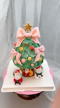 a decorated christmas tree on top of a book with pink bows and ornaments around it