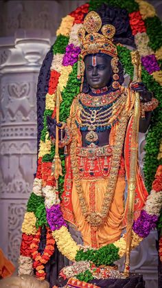 a statue of the hindu god maha in front of a floral display at a temple