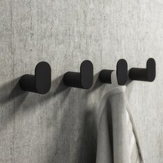 three black hooks are hanging on the wall next to a gray towel rack and white towels