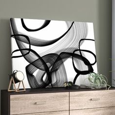 a black and white abstract painting on a wall above a dresser in a living room