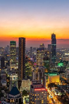 the cityscape is lit up at night with bright lights and skyscrapers in the background