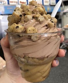 a person holding a cup filled with ice cream and chocolate chip cookies