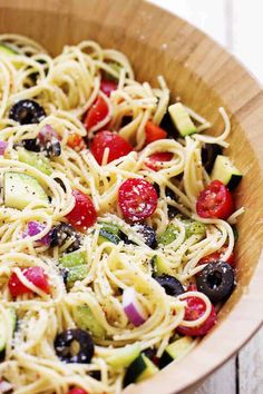 a close up view of a pasta salad with olives, tomatoes and cucumbers