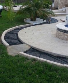 a backyard with a pool and hot tub surrounded by landscaping materials in the grass, next to a palm tree