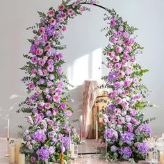 an arch made out of flowers with candles on the floor and other decorations around it