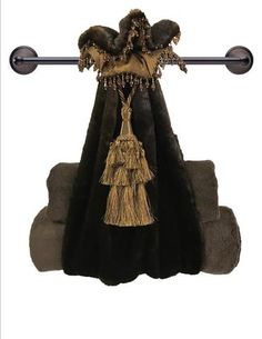 a black and gold dress hanging from a metal rod with tassels on it