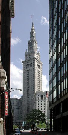 a tall building with a spire on top in the middle of a busy city street