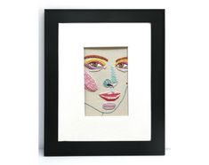 a framed art piece with an image of a woman's face painted on it