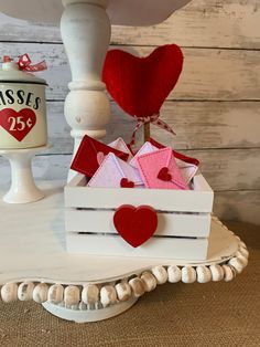 a small white box with red hearts on it sitting on a table next to a vase