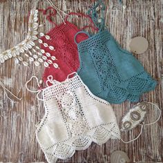 three crocheted bras are displayed on a wooden table with other items in the background