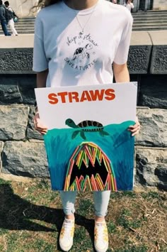 a girl holding up a sign with the words straws on it and a drawing of a sea turtle