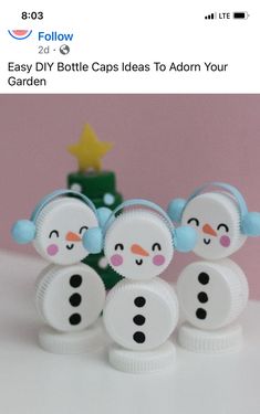 three snowmen made out of plastic bottle caps sitting on top of a white table