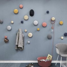 a blue wall with many different colored balls on it and a gray chair in the foreground