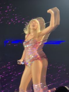 a woman in a bodysuit on stage with her arms up and legs spread out