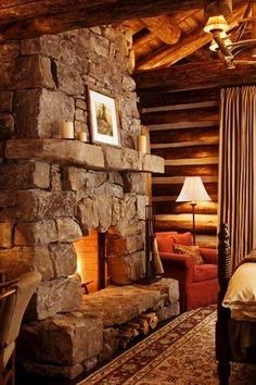 a rustic bedroom with stone fireplace and bed