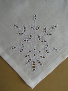 a white table cloth with an embroidered snowflake design