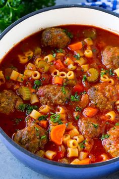 a bowl filled with meatballs and pasta soup on top of a blue table cloth