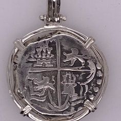 a silver pendant with an anchor and cross on it