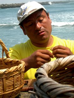 a man in a yellow shirt is holding some food by the ocean and looking at it