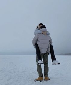 two people standing in the snow hugging each other