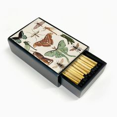 an open matchbox filled with matches and moths on white paper next to each other