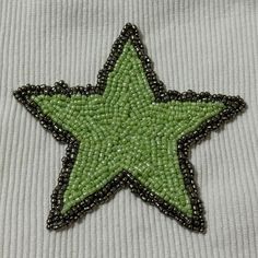 a green and black beaded star on a white shirt