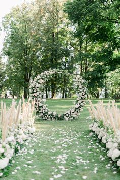 an outdoor ceremony with white flowers and greenery on the grass, surrounded by trees